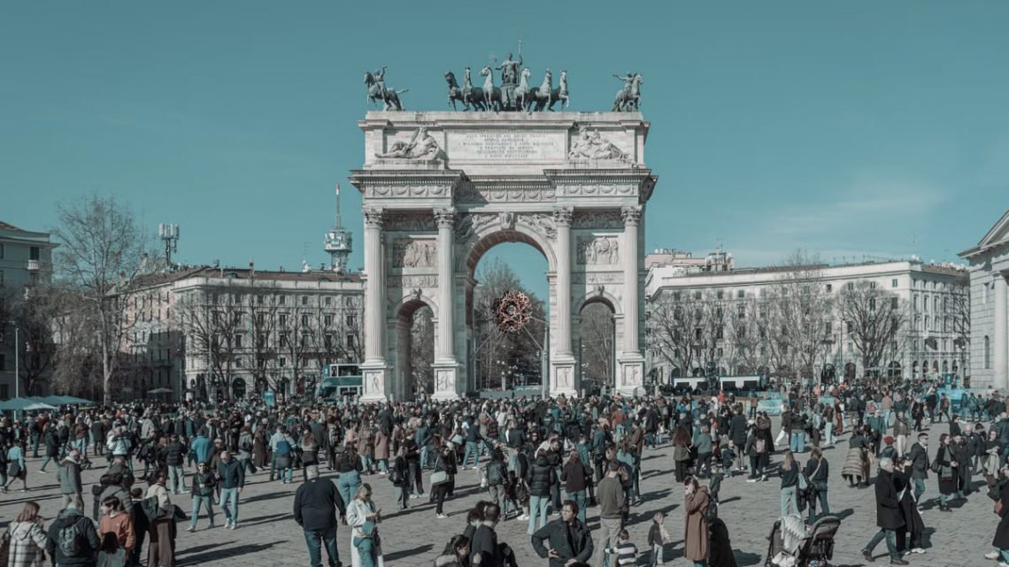 A bustling scene at Arco della Pace in Milan, capturing diverse people under a clear sky.