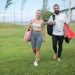 Couple walking in Lisbon park with yoga mats, showcasing active lifestyle in natural setting.